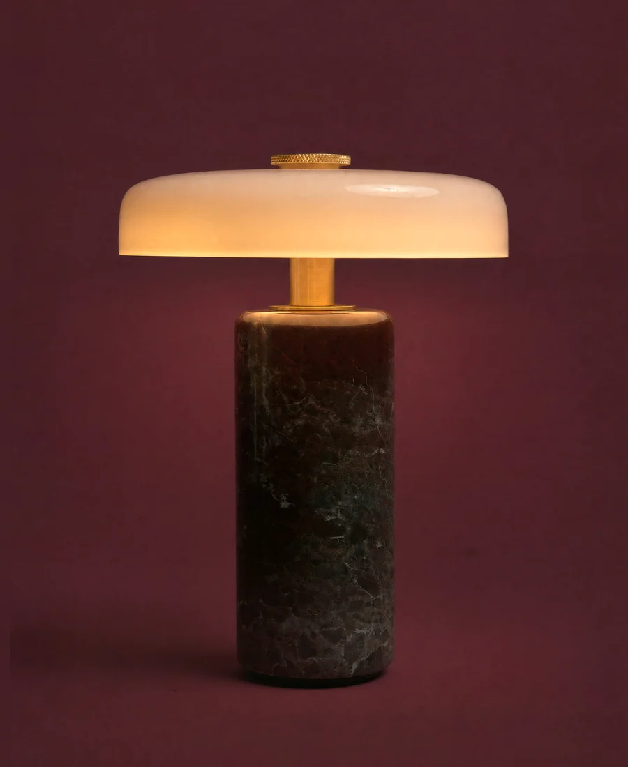 A stone lamp with an opal glass disc. Lit.