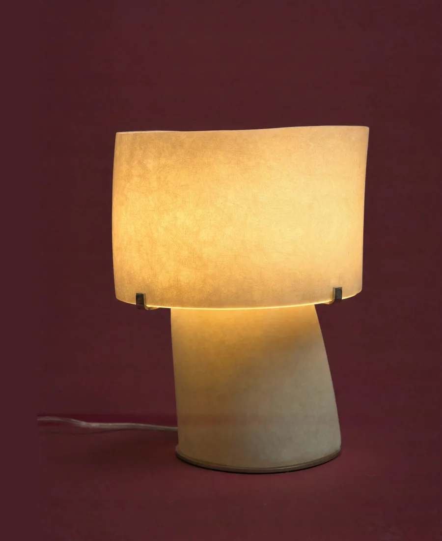 A parchment shade lamp. Lit.